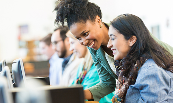 woman leaning next to a girl helping with something on a computer