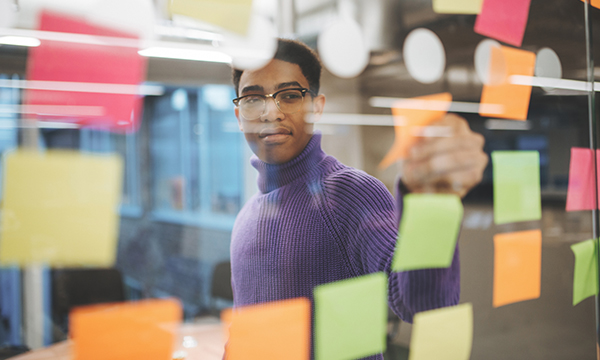 man behind glass wall of sticky notes