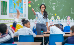 Smiling Teacher in front of group of students in classroom