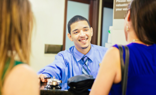 Smiling desk clerk checking in two people