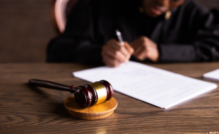 Gavel in foreground, with judge signing papers in background