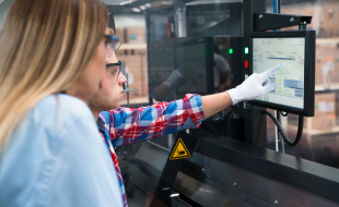 Two workers looking at a screen in a manufacturing plant